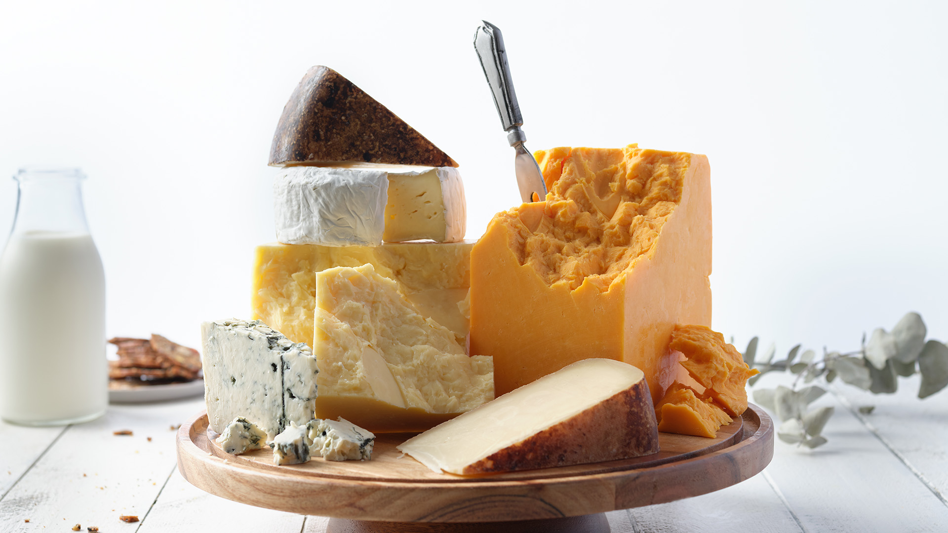 A round wooden board with wedges of various types of Ontario cheeses.