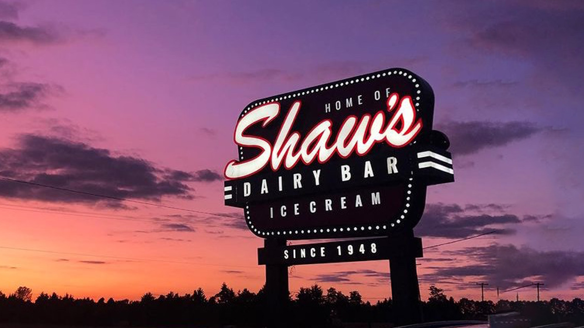 An image of the Shaw's Ice Cream sign outside of their parlour at sunset.