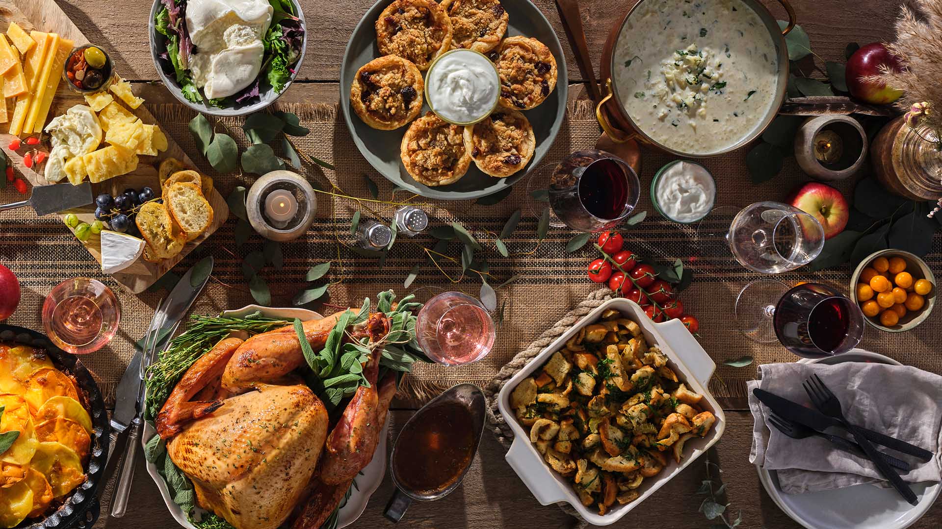 Overhead view of a harvest table featuring a smoked turkey, stuffing and other fall inspired recipes.