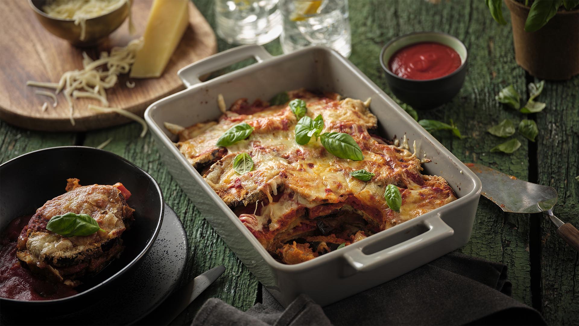Side shot of eggplant parmigiana in rectangular white dish with handles.