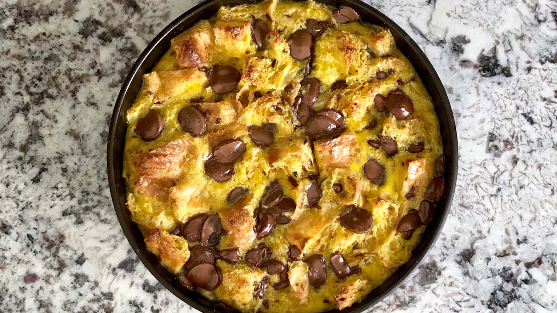 Overhead shot of croissant bread pudding in round cast iron pan.