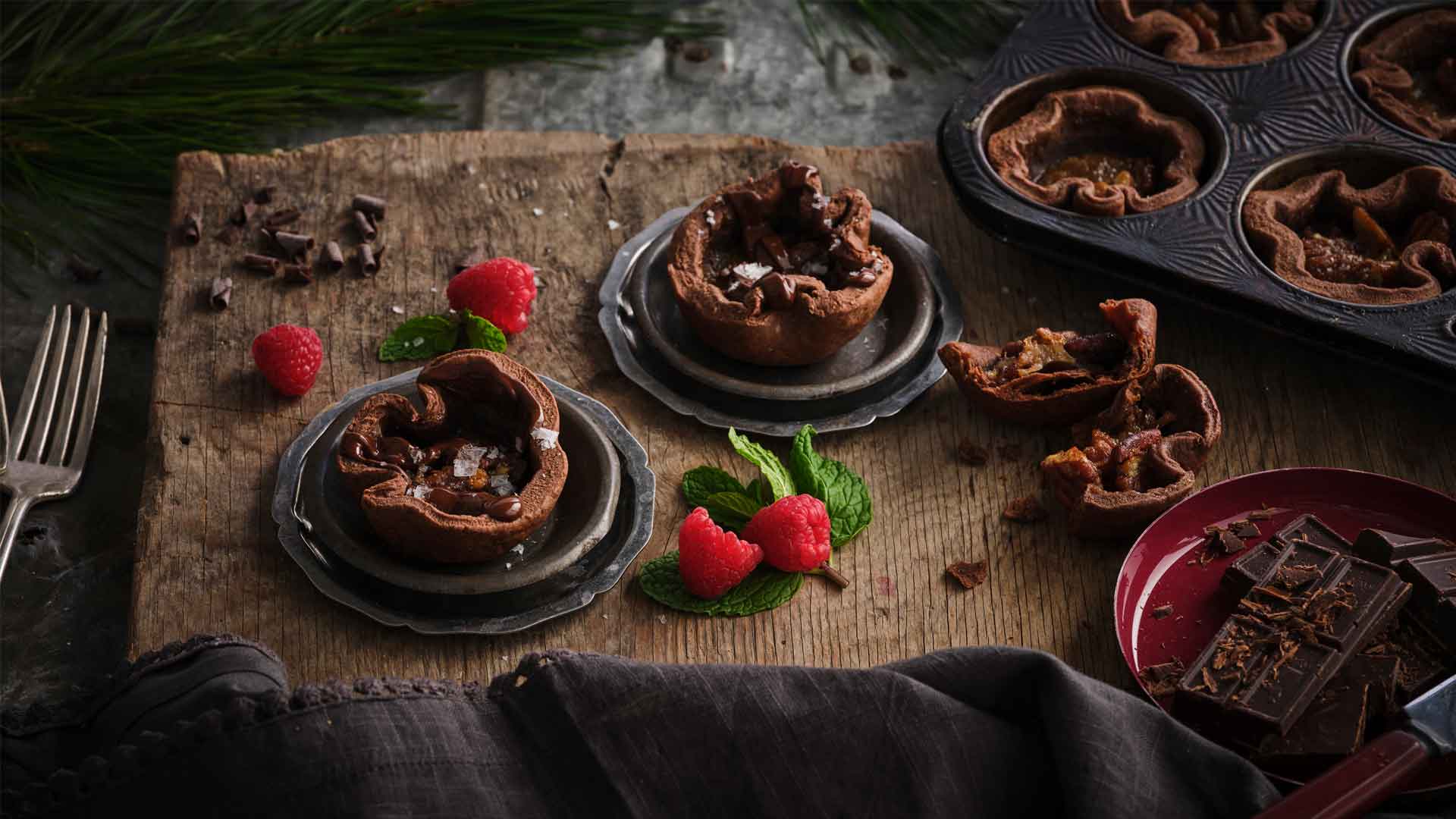 Chocolate butter tarts with flakes of sea salt on top on wooden serving board.